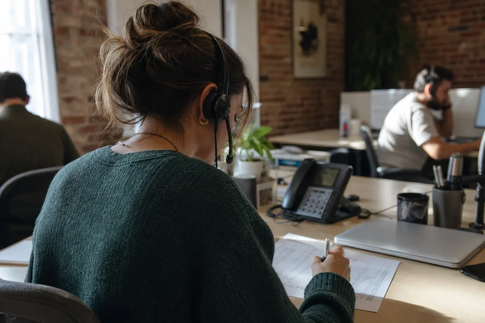 Sales rep on a phone call ticking off prospects on a paper call sheet